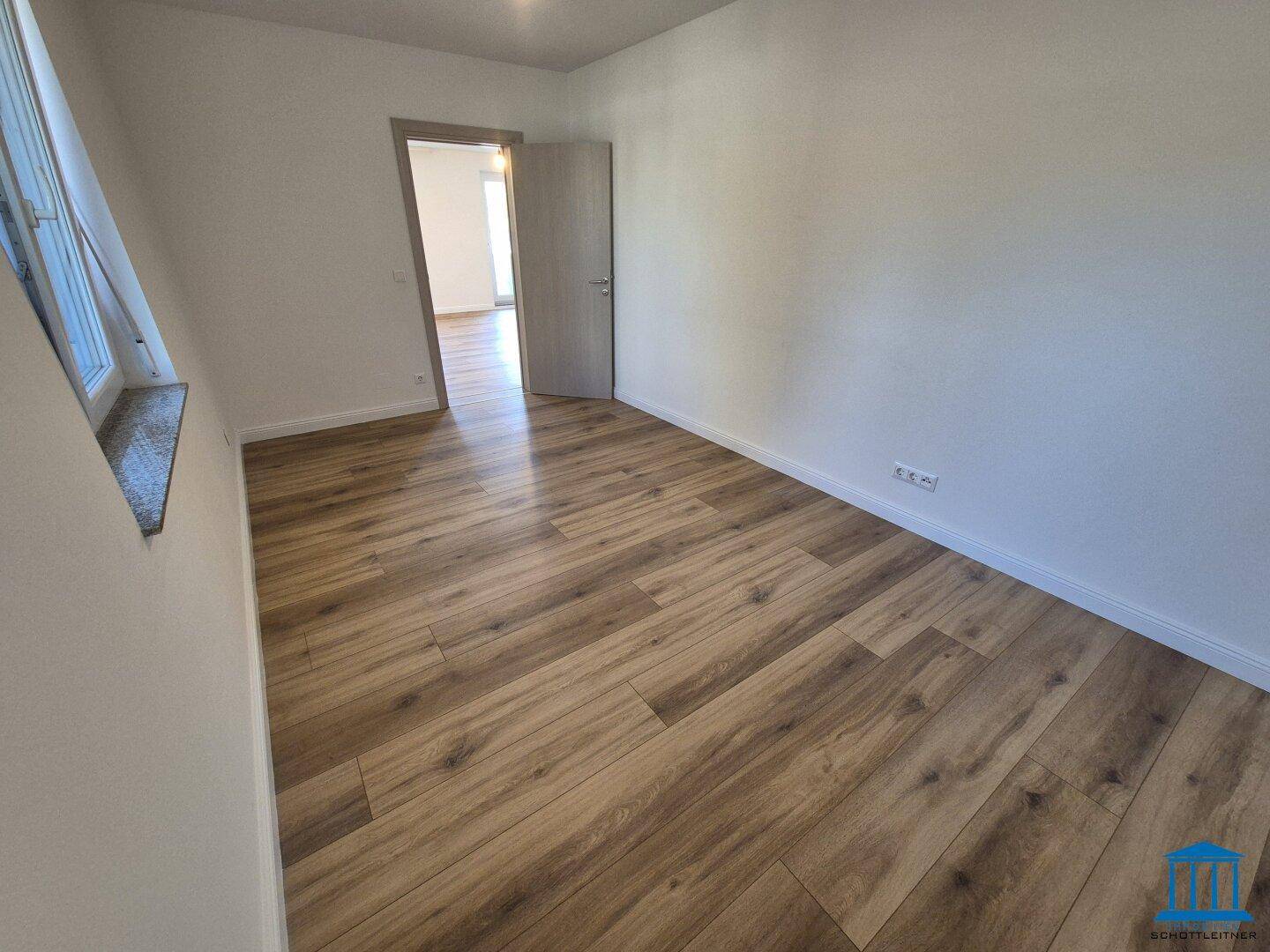 Helles Schlafzimmer mit neuem Laminatboden und weiß gestrichenen Wänden.