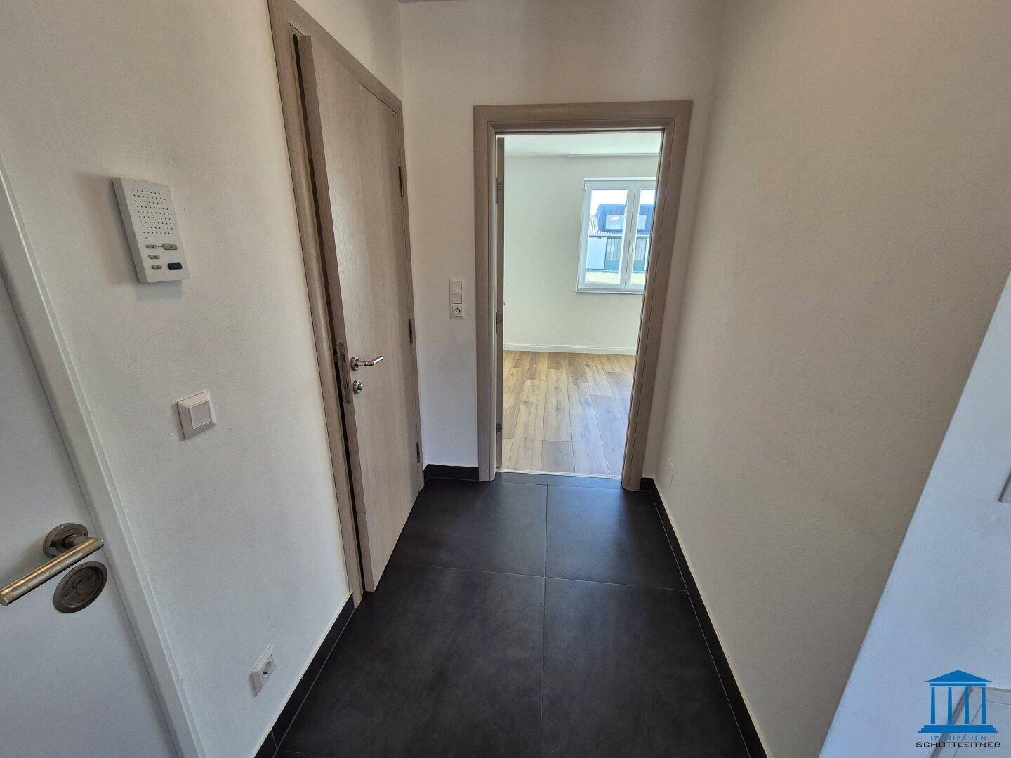 Moderner Flur mit dunklen Fliesen und mehreren Türen zu den angrenzenden Räumen.