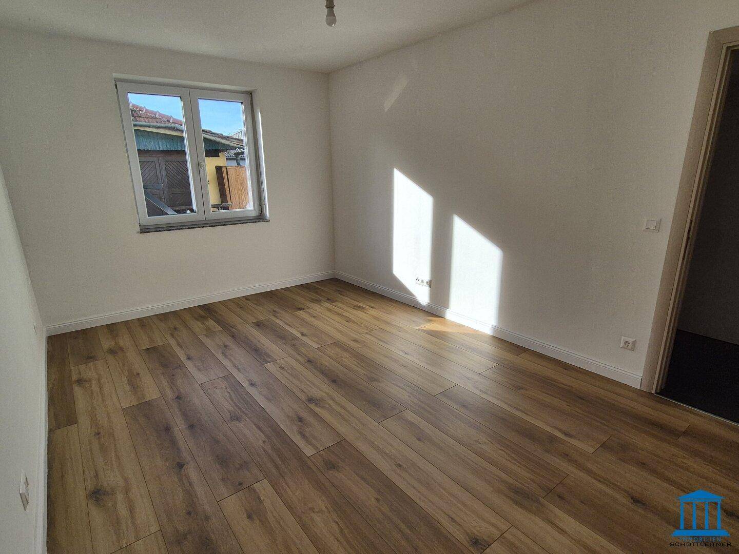 Sonniger Raum mit Laminatboden und weißen Wänden, ideal als Schlafzimmer oder Kinderzimmer.