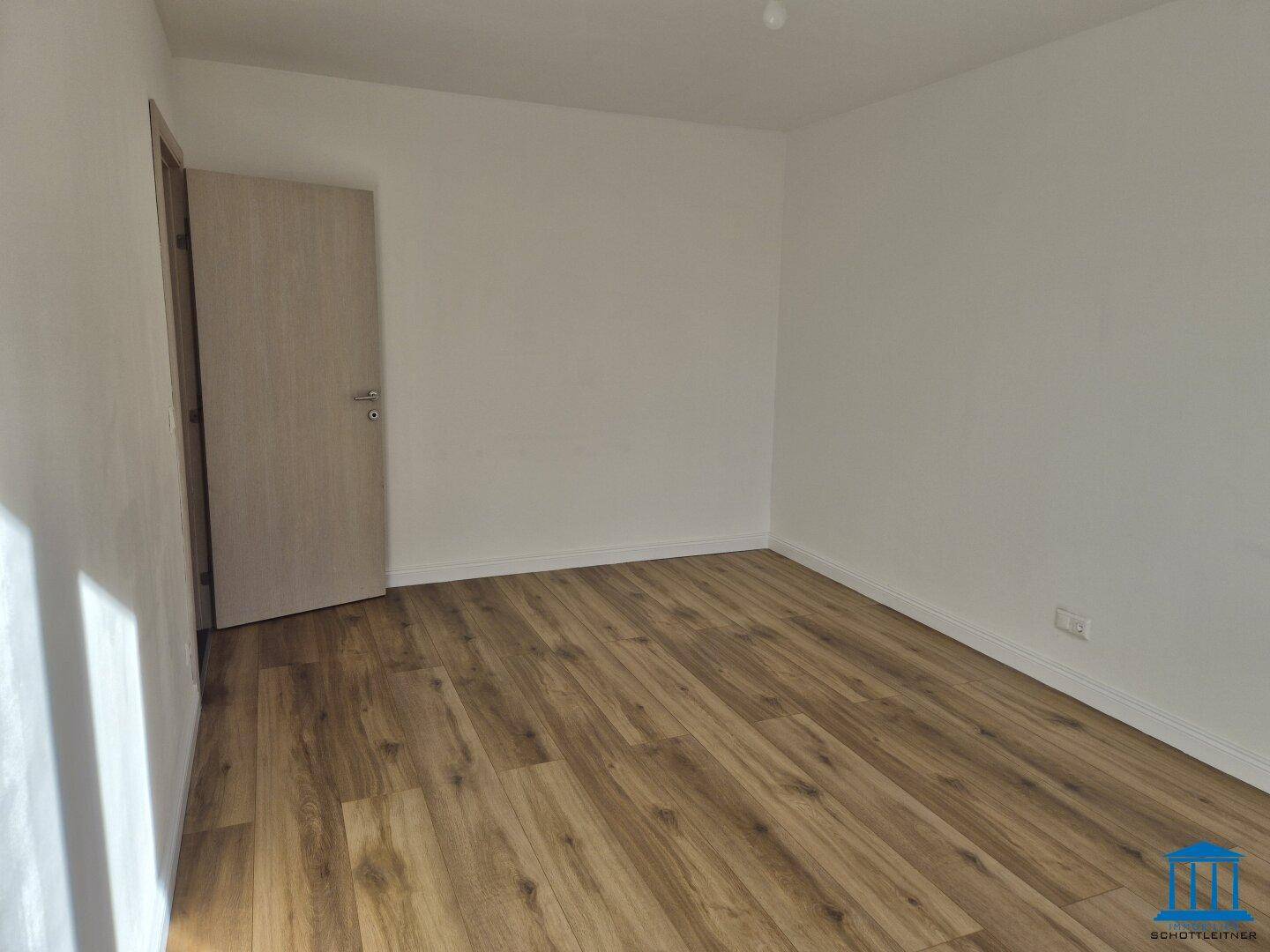 Ruhiges Schlafzimmer mit Laminatboden und weiß gestrichenen Wänden, bereit zum Einzug.