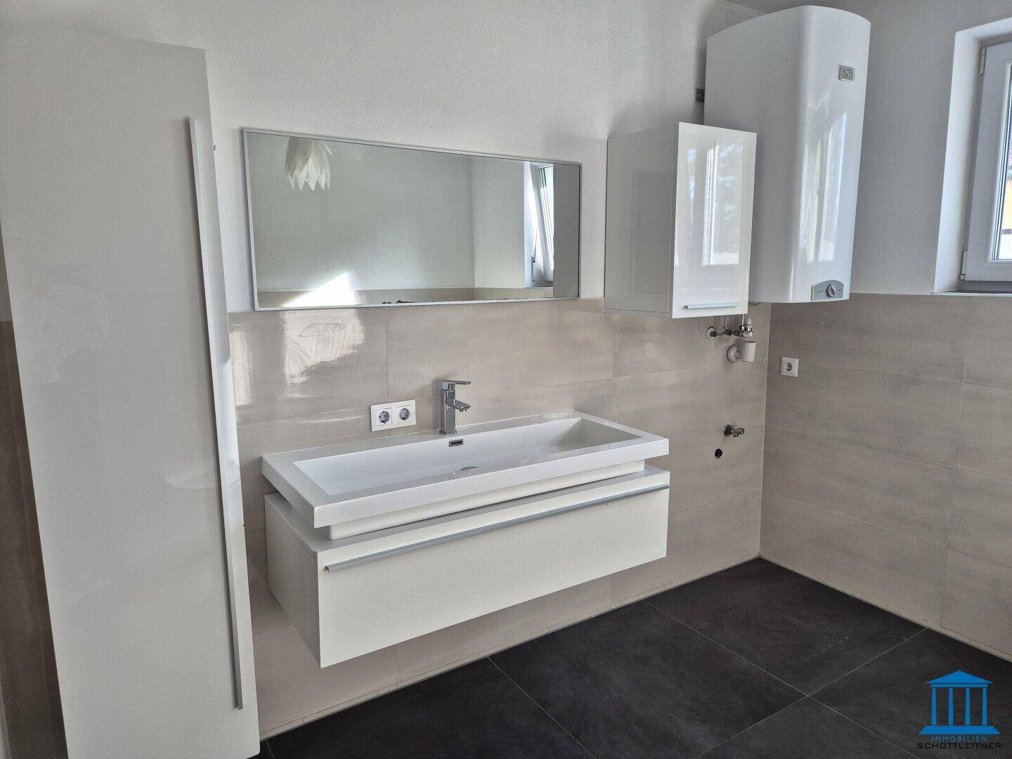 Heller Waschtisch mit Einzelwaschbecken, Spiegelschrank und modernem Design im Badezimmer.