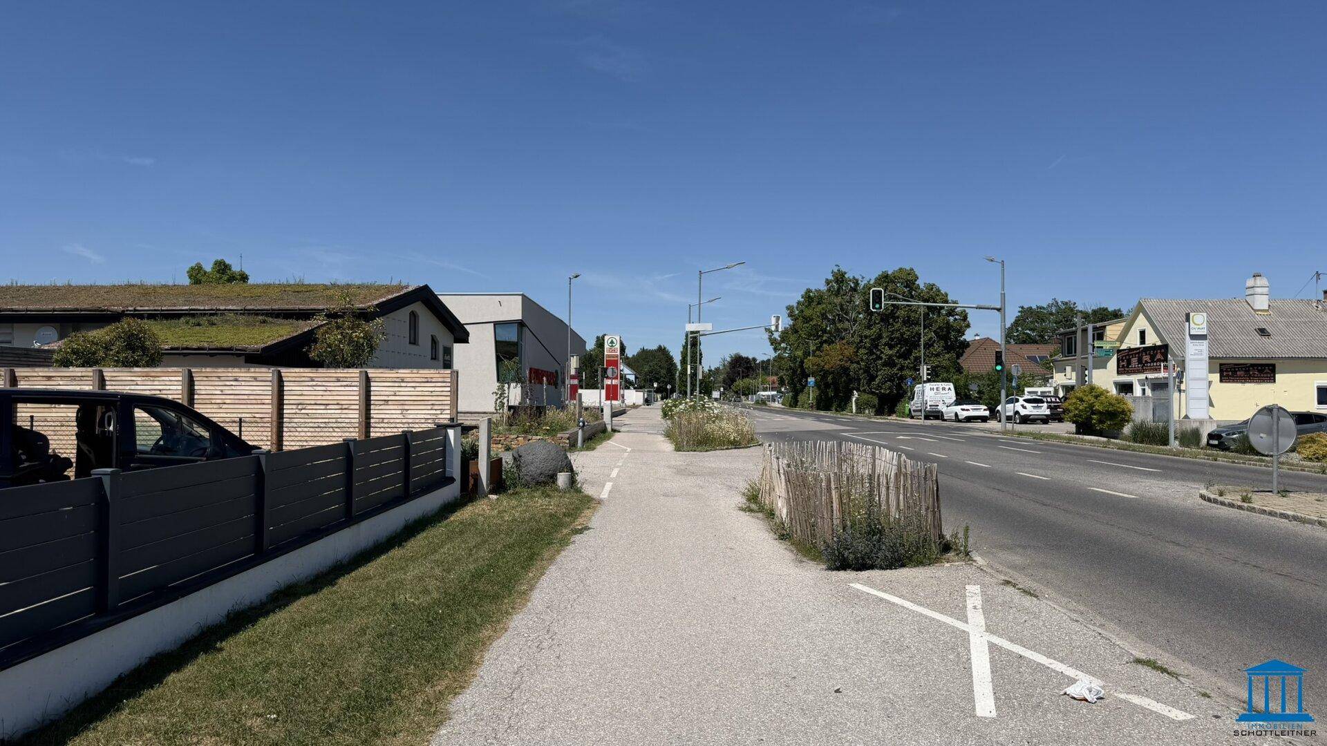 Ruhige Straße mit Bürgersteig und Wohnhäusern im Hintergrund unter klarem Himmel.
