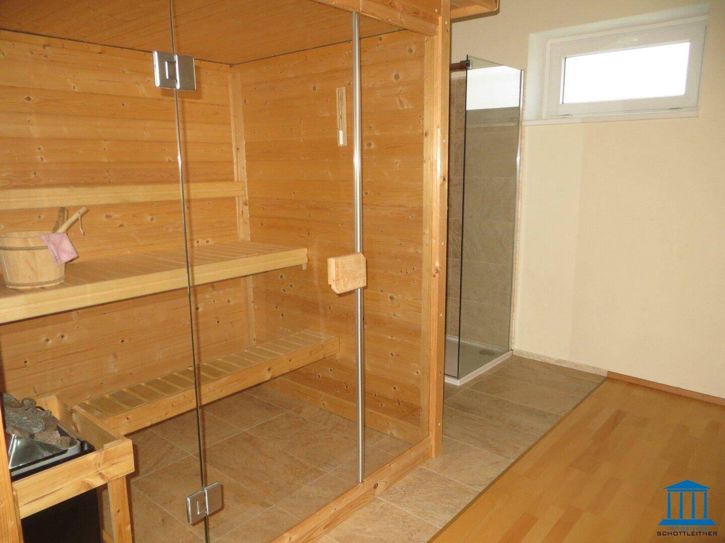 Moderne Holzsauna mit Glasfront und angrenzender Dusche, ideal für Entspannung.