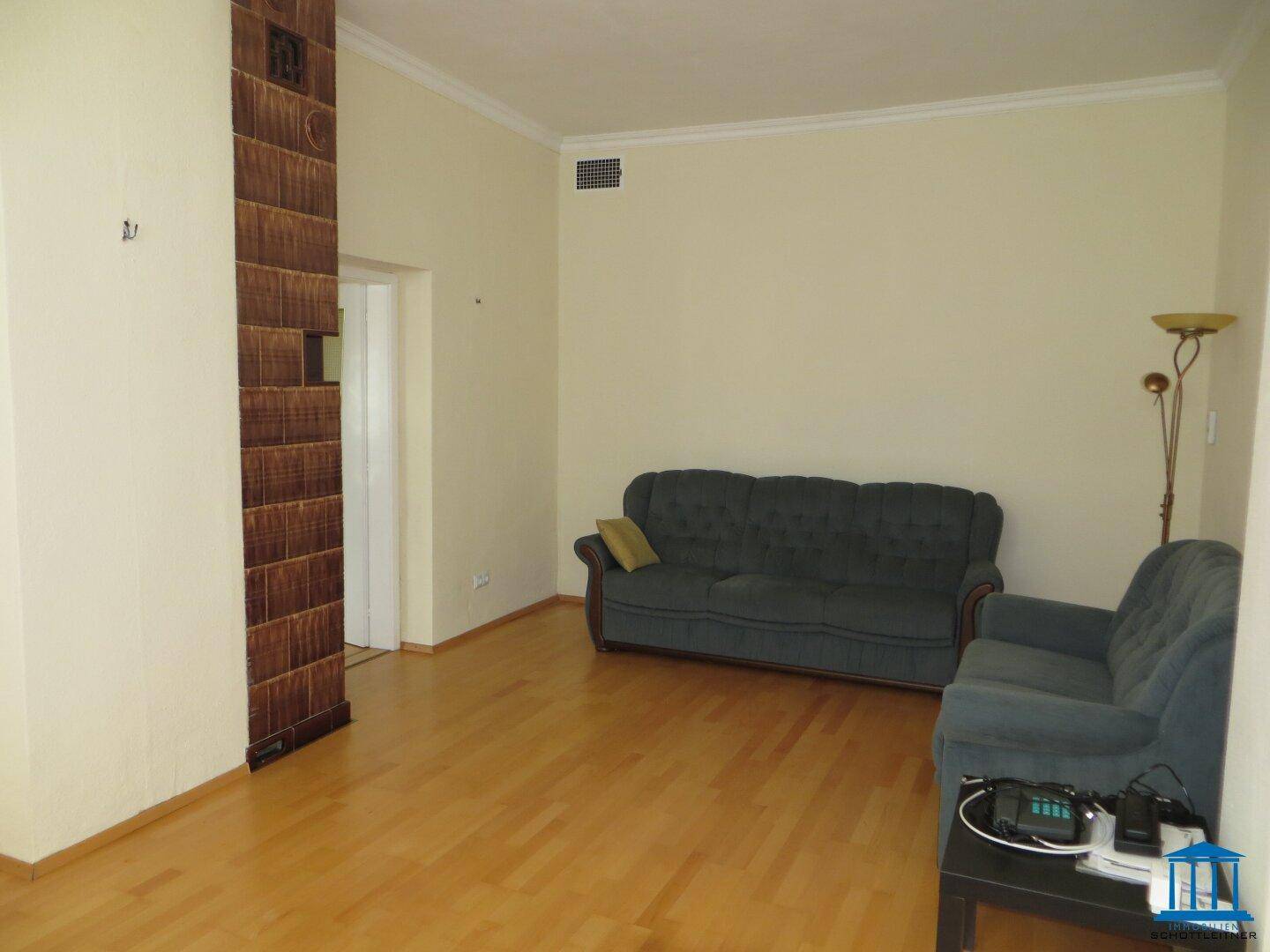 Gemütliches Wohnzimmer mit zwei Sofas und einem dekorativen Kachelofen-Element.