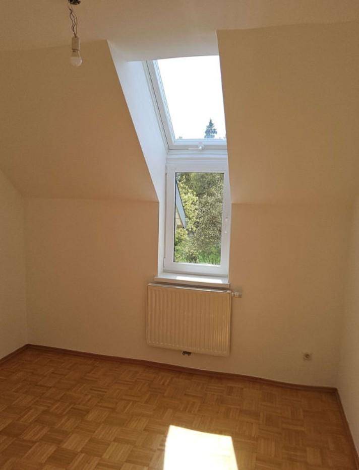 Helles Zimmer mit Parkettboden, Dachfenster und Blick ins Grüne, ideal als Schlafzimmer.