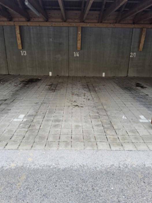 Überdachte Parkplätze mit nummerierten Stellflächen und Betonwänden in gutem Zustand.