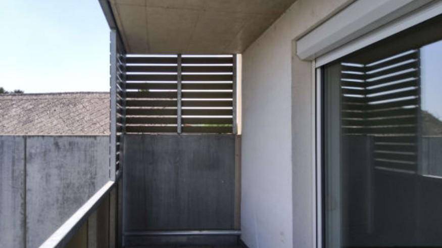 Balkon mit Betonwänden und Lamellenverkleidung für Privatsphäre, bietet einen geschützten Außenbereich.