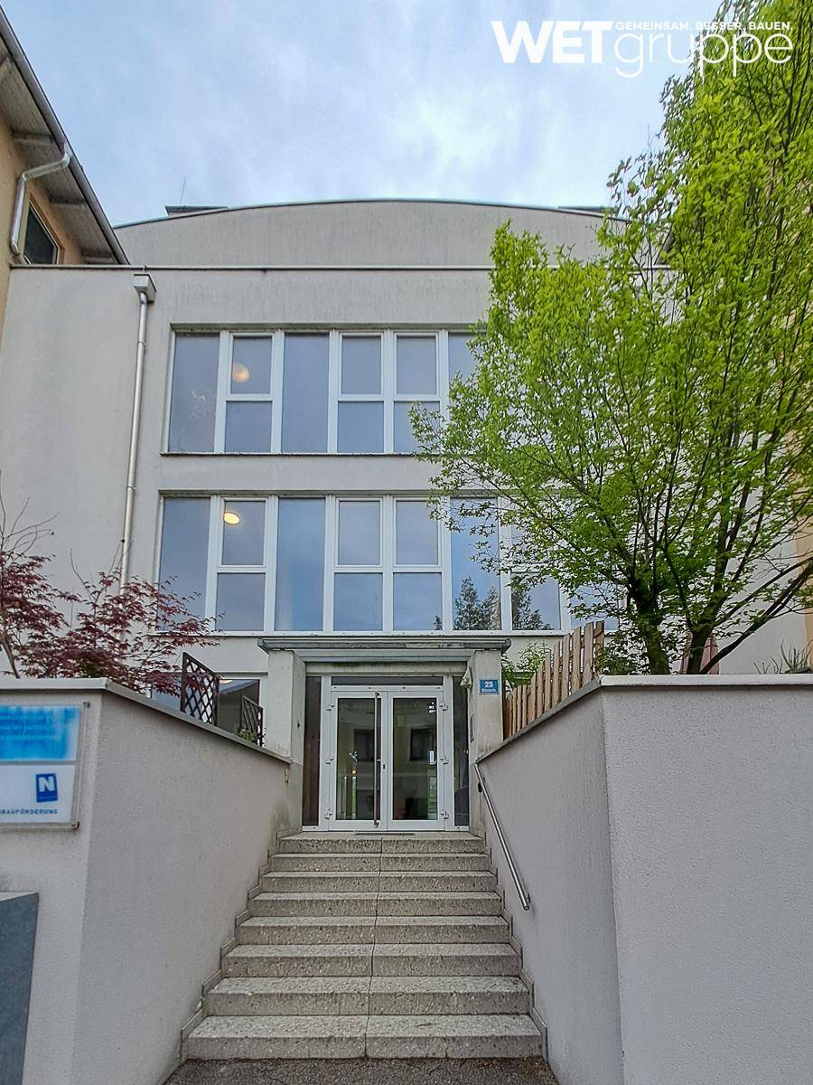 Modernes Gebäude mit breiter Treppe zum Eingang und großen Fenstern in der Fassade.