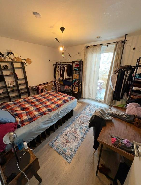 Schlafzimmer mit Doppelbett, Kleiderständern und Zugang zu einem Außenbereich.