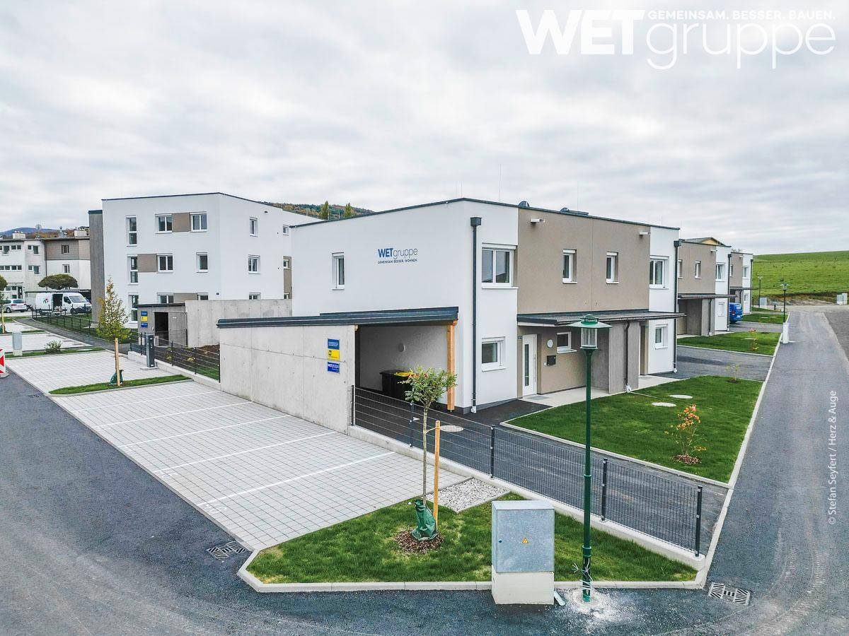 Übersicht einer neuen Wohnsiedlung mit modernen Häusern, Grünflächen und gepflasterten Parkplätzen.