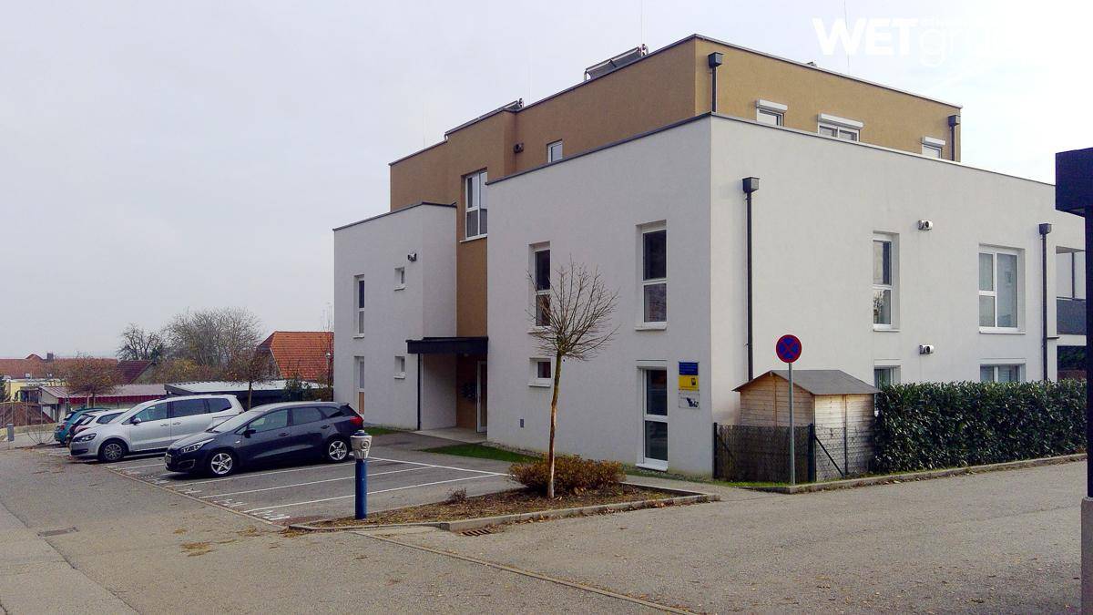 Weitläufige Außenansicht des modernen Gebäudes mit Parkplätzen und umliegender Landschaft.