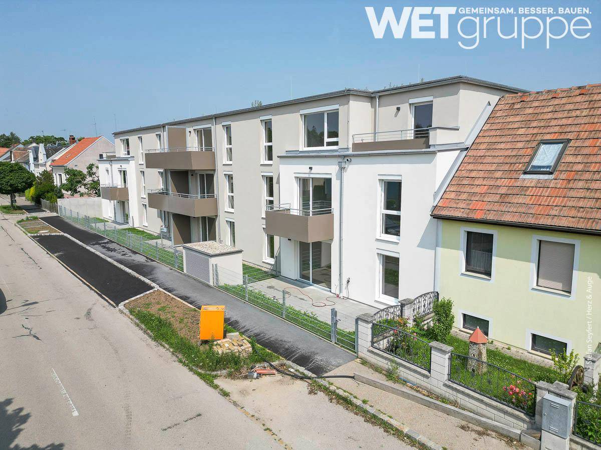 Moderne Wohnanlage mit mehreren Balkonen und Terrassen, gelegen an einer ruhigen Straße.
