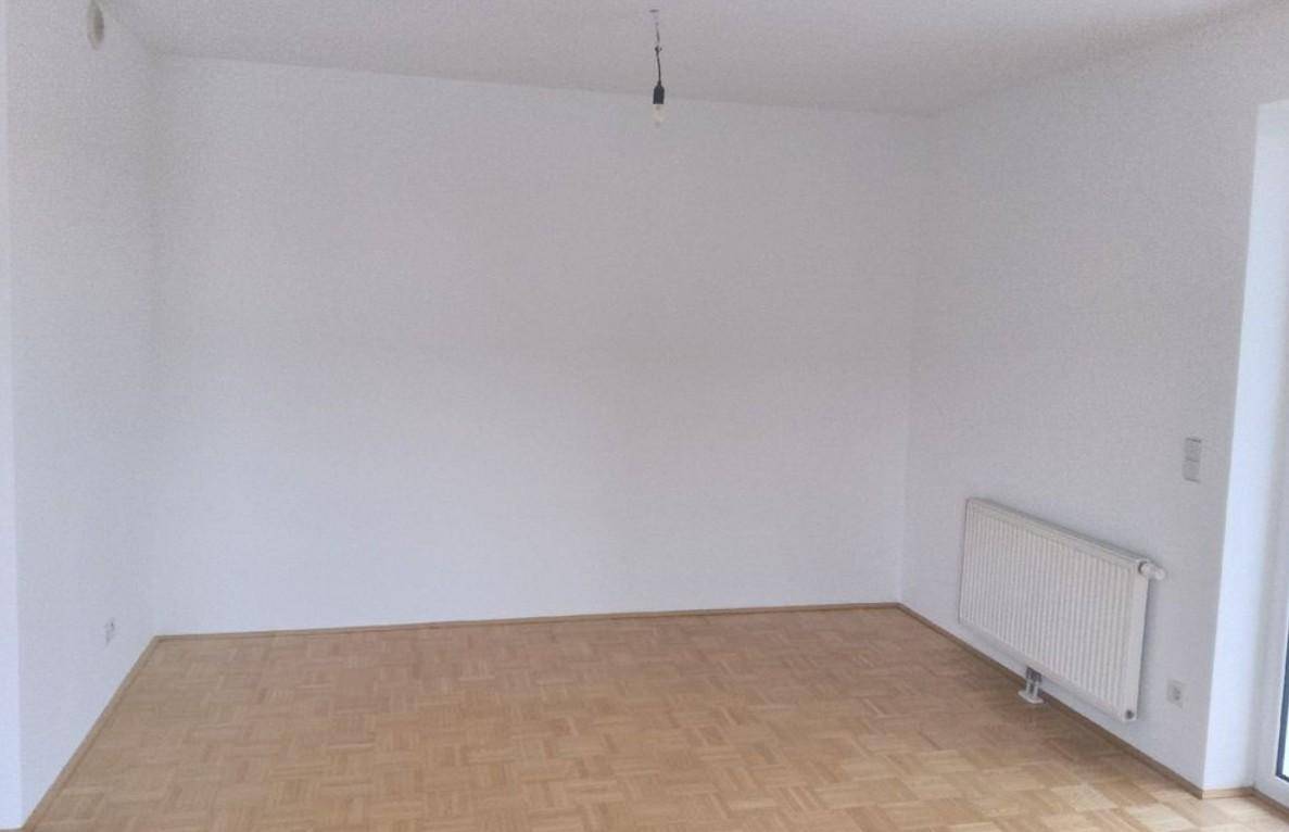 Schlichter, heller Raum mit Parkettboden und Heizkörper, bereit zur individuellen Gestaltung.