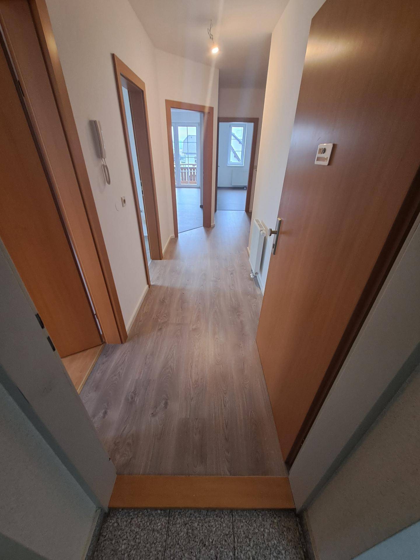 Heller Flur mit Laminatboden und mehreren Türen, die zu verschiedenen Räumen führen.