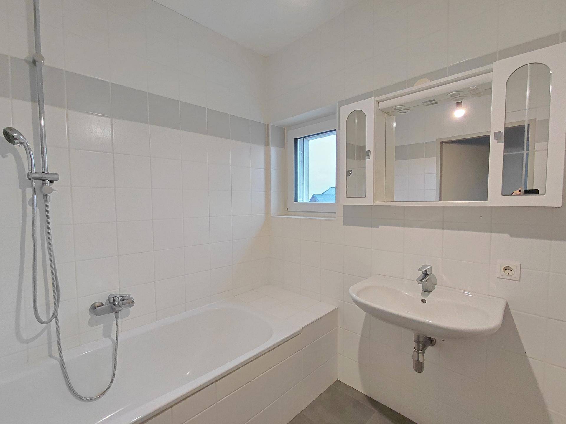Helles Badezimmer mit Badewanne, Duschfunktion, Waschbecken und Fenster, in gutem Zustand.