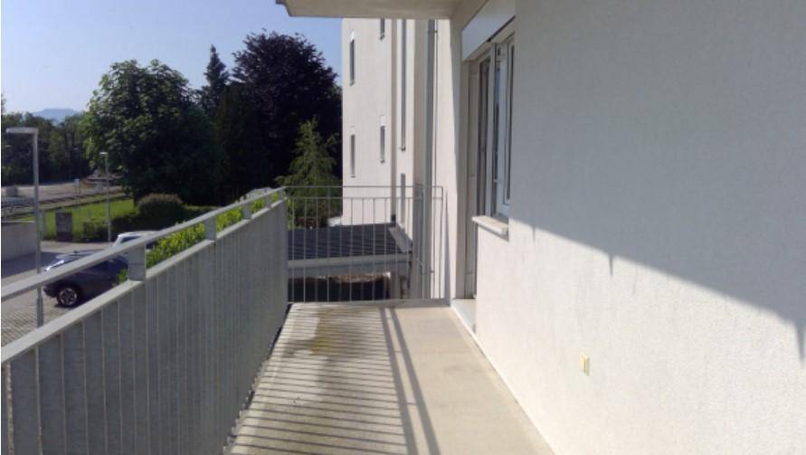 Geräumiger Balkon mit Metallgeländer und sonnigem Blick ins Grüne.