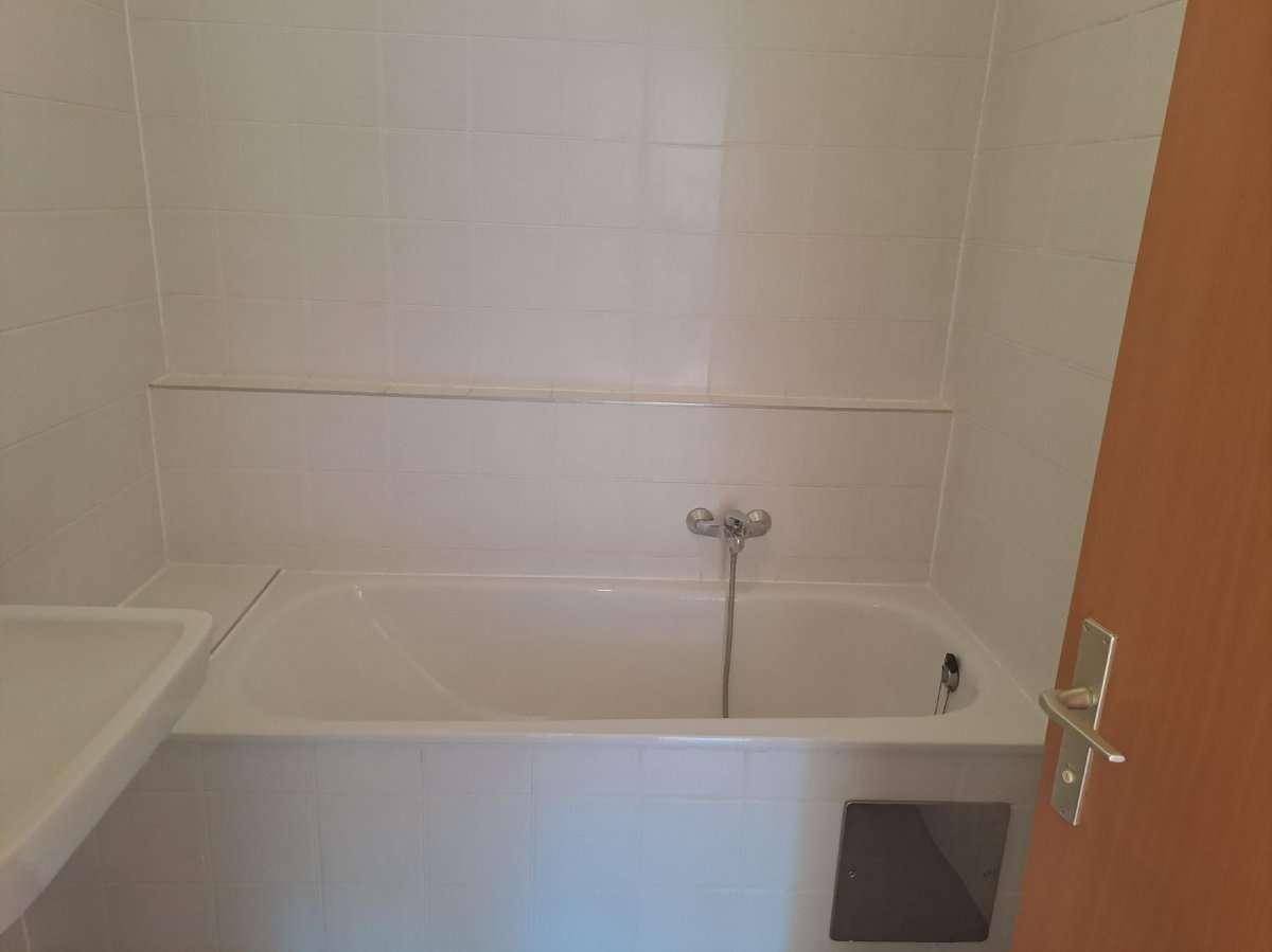 Badezimmer mit weiß gefliesten Wänden, Badewanne und Waschbecken.