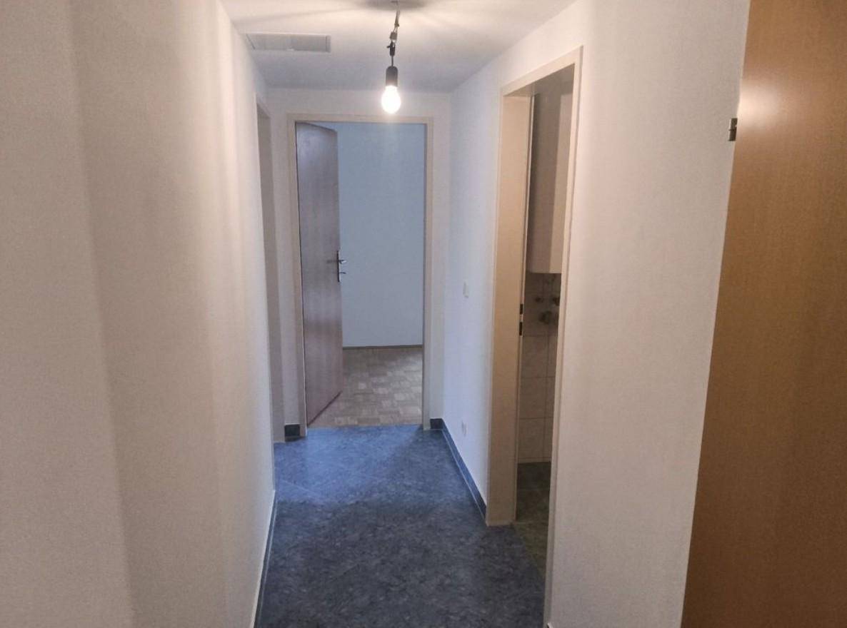 Schlichter Flur mit dunklem Bodenbelag und Zugang zu verschiedenen Zimmern der Wohnung.