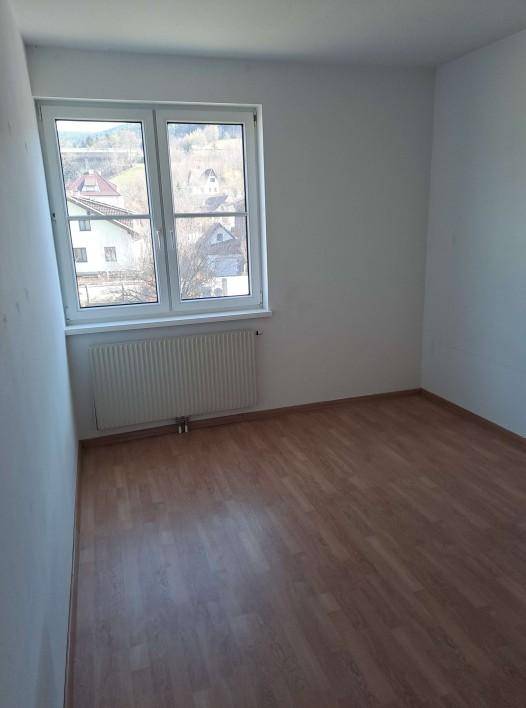 Helles Schlafzimmer mit Holzboden, weiß gestrichenen Wänden und Blick auf die Umgebung.