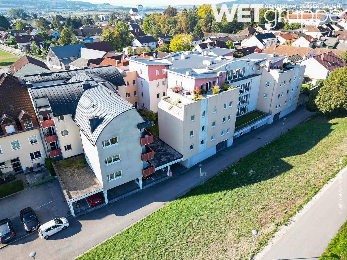 Luftaufnahme einer modernen Wohnanlage mit Flachdächern, Balkonen und angrenzenden Grünflächen.