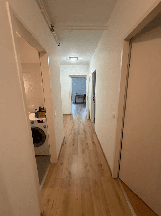 Langer Flur mit hellem Laminatboden und Zugang zu verschiedenen Wohnbereichen.