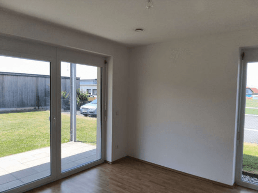 Heller Innenraum mit großen Glasfronten und direktem Zugang zum Garten.