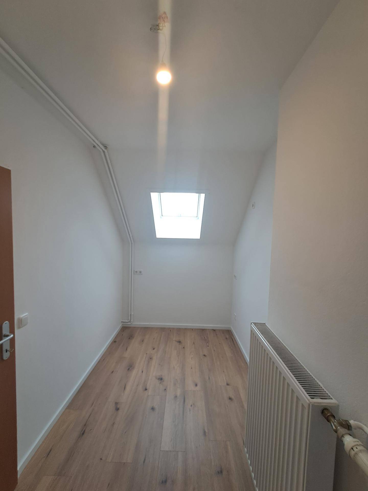 Heller Raum im Dachgeschoss mit Holzboden und Dachfenster, geeignet für verschiedene Nutzungen.