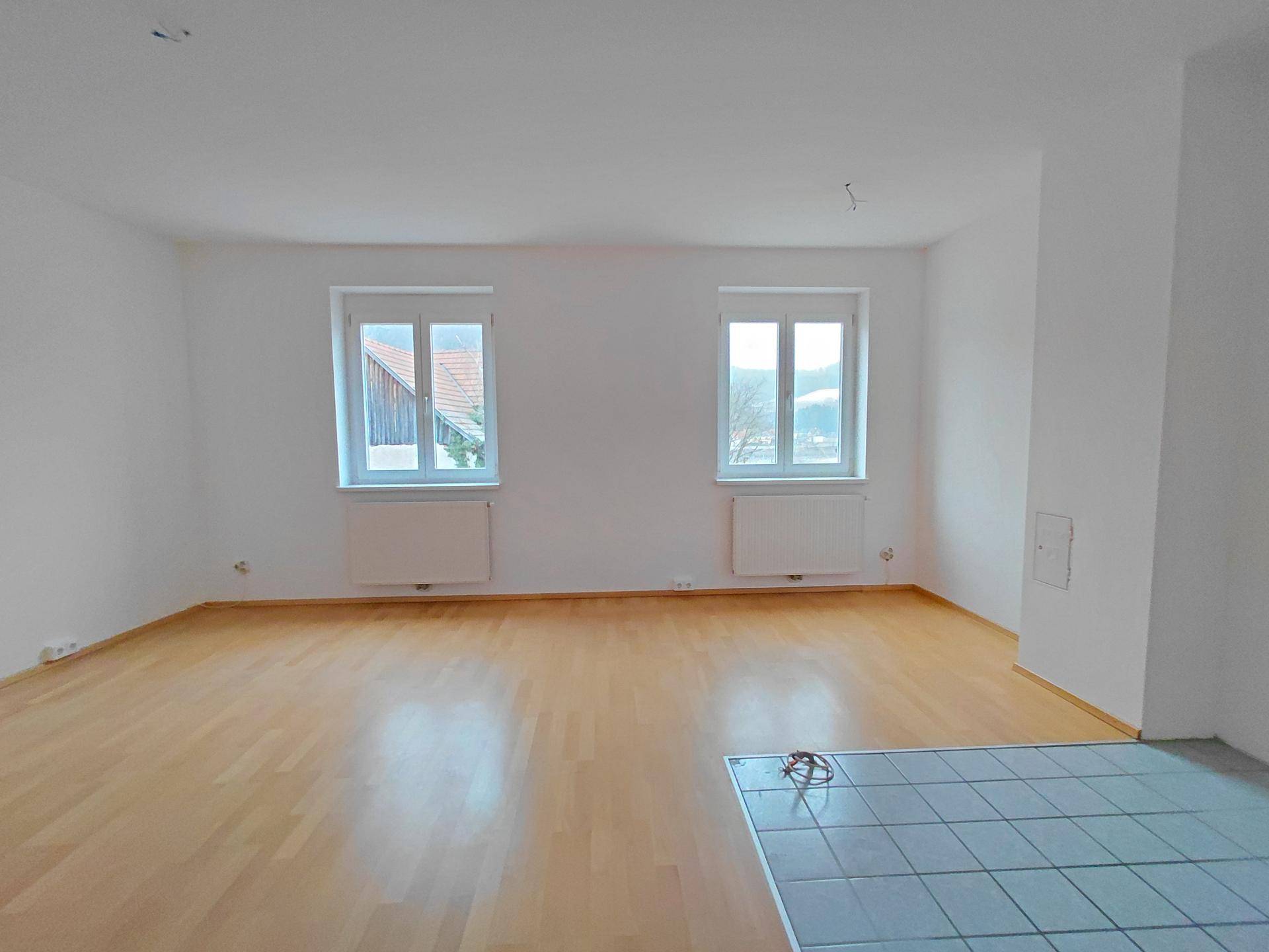 Helles, leeres Zimmer mit Parkettboden und zwei Fenstern, bereit zur individuellen Einrichtung.