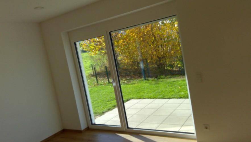 Heller Raum mit großem Fenster und Zugang zur Terrasse, bietet einen schönen Blick ins Grüne.