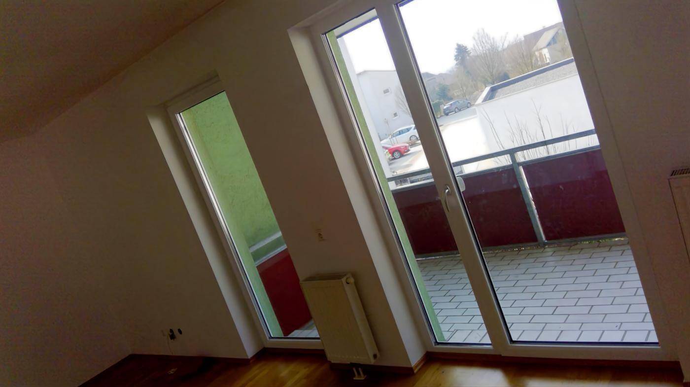 Heller Raum mit Holzboden und Zugang zu einem Balkon, der viel Licht bietet.