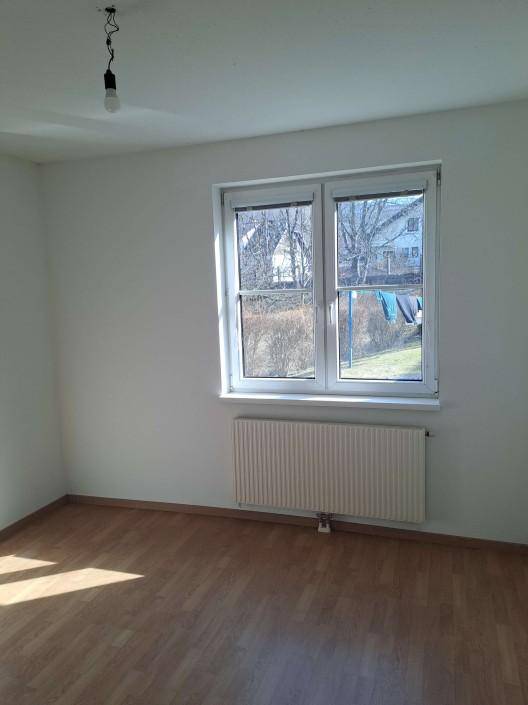 Sonniger Raum mit Laminatboden und Fenster, das viel Tageslicht hereinlässt, ideal als Schlafzimmer.