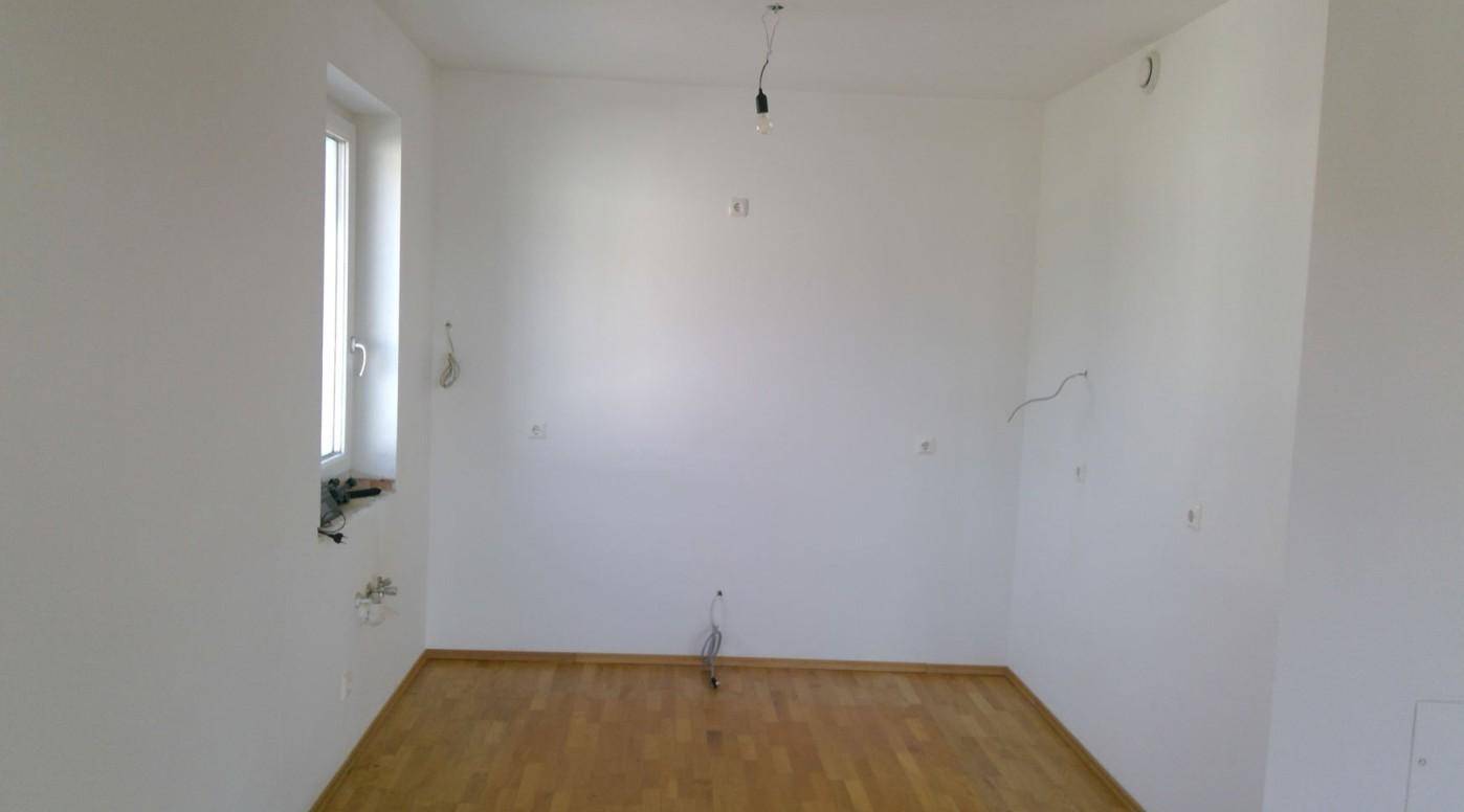 Heller Raum mit Holzboden und einem Fenster, das natürliches Licht hereinlässt.