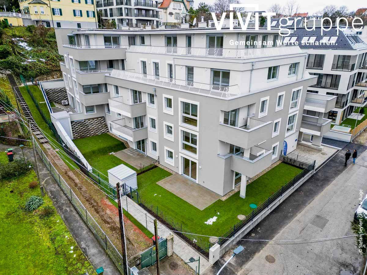 Gesamtansicht der modernen Wohnanlage in hügeliger Umgebung mit viel Grün.