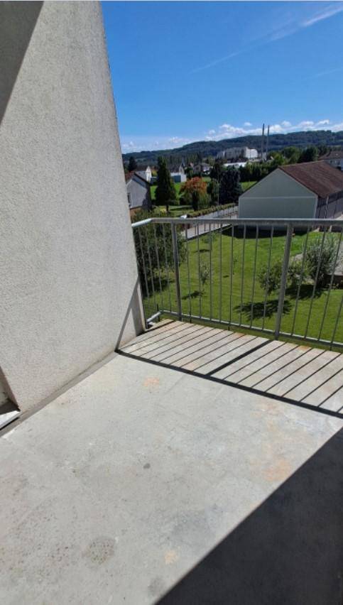 Balkon mit Blick auf grüne Landschaft und entfernte Hügel unter blauem Himmel.