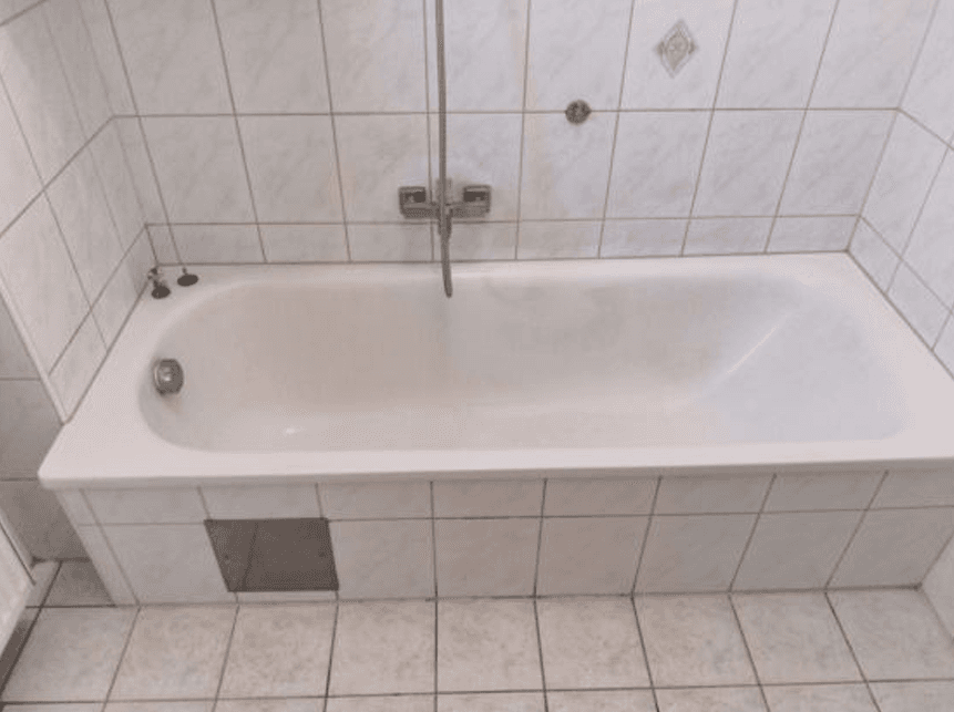 Badezimmer mit weißer Badewanne und hellen Fliesen an Wänden und Boden.