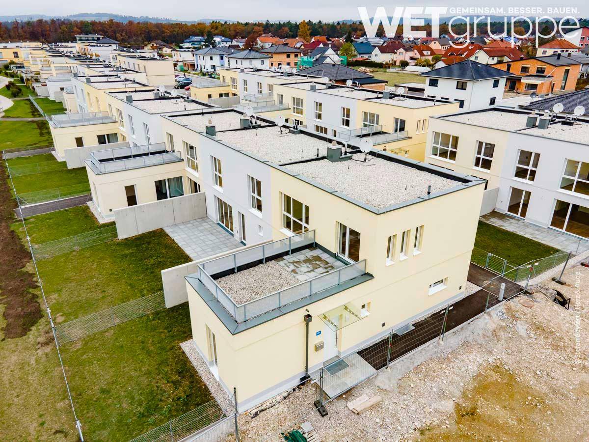 Reihenhäuser in einer Neubausiedlung mit Flachdächern und privaten Gärten.