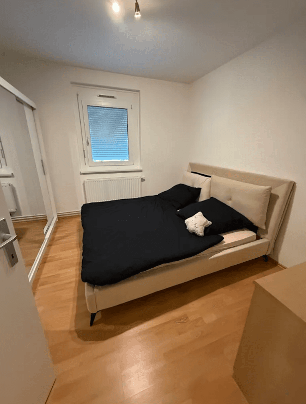 Schlafzimmer mit Doppelbett, Laminatboden und Fenster mit Rollladen, hell und gemütlich.