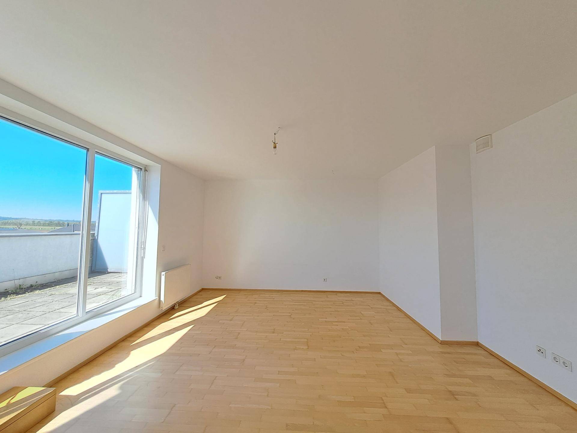 Geräumiges Wohnzimmer mit Holzboden und großen Schiebetüren zur Terrasse.