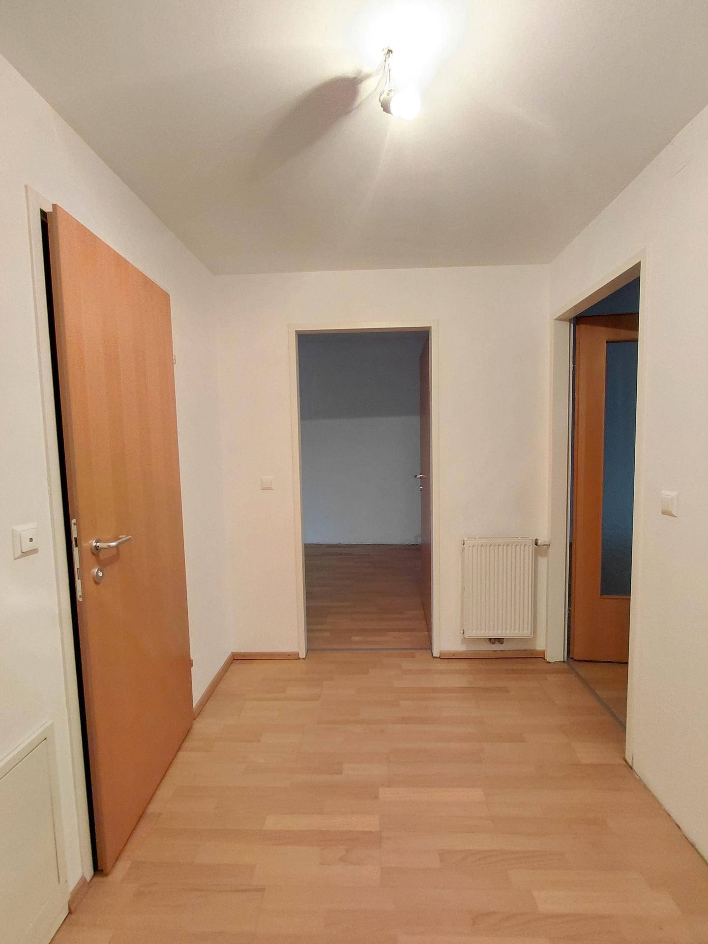 Heller Flur mit Holztüren und Parkettboden, der zu verschiedenen Räumen der Wohnung führt.