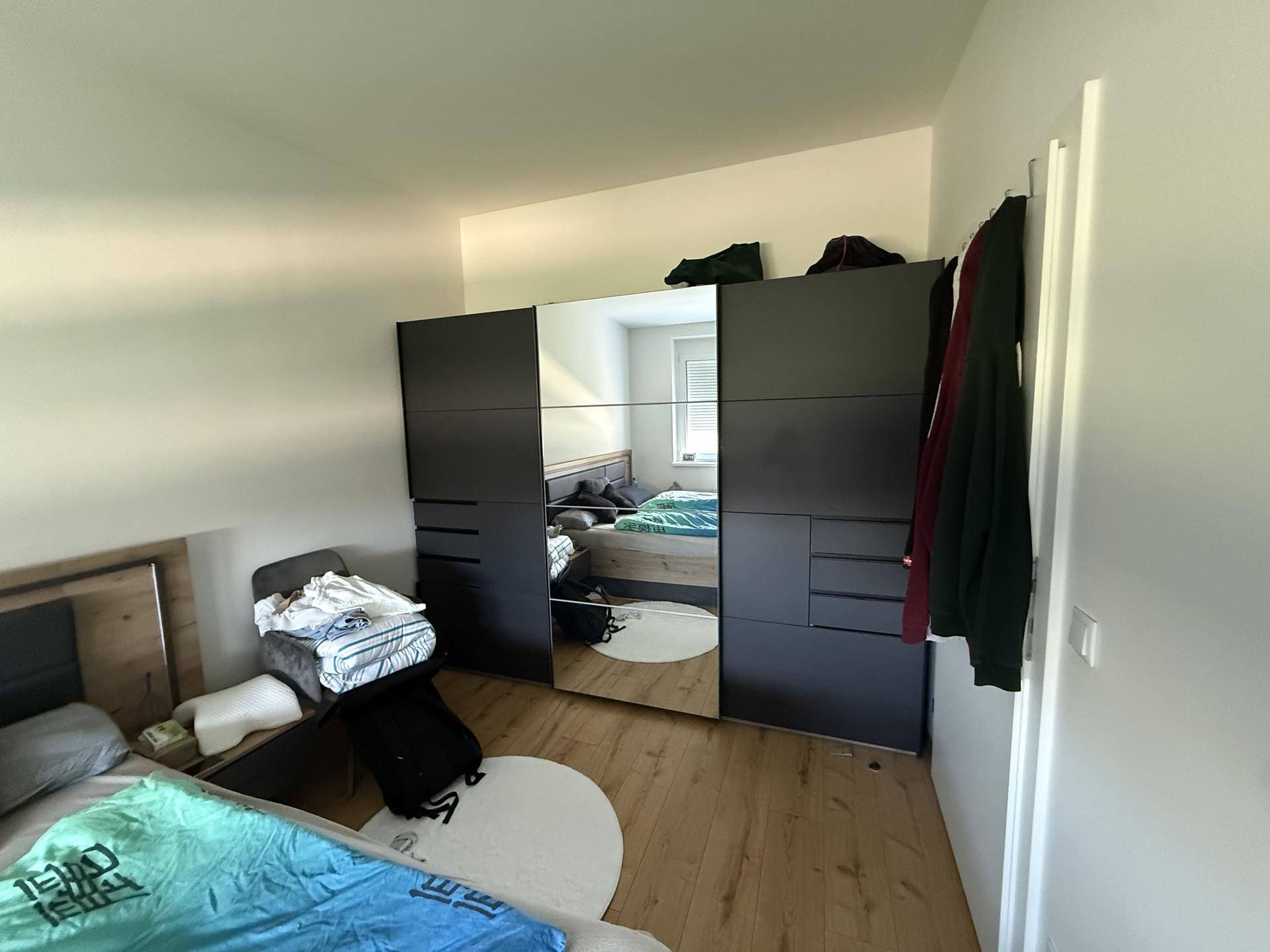 Schlafzimmer mit großem Kleiderschrank mit Spiegeltüren und hellem Holzboden für viel Stauraum.