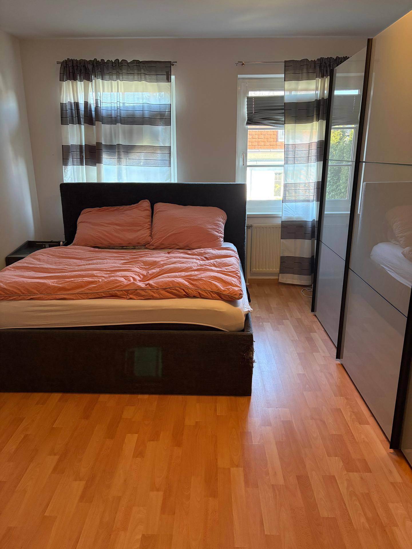 Schlafzimmer mit Doppelbett, Kleiderschrank und Laminatboden.