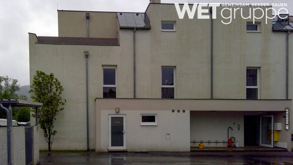 Rückansicht des modernen Wohngebäudes mit schlichter Fassade und einigen Fenstern.