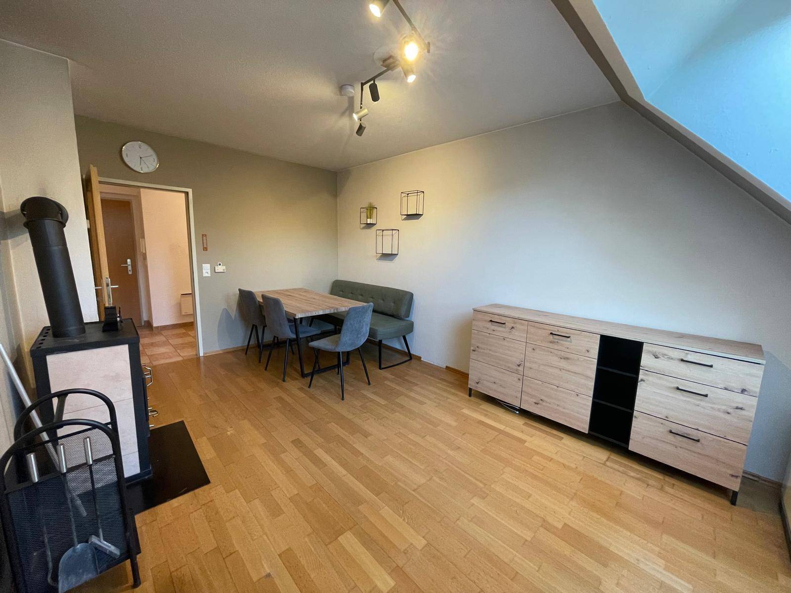 Gemütlicher Wohn-Essbereich mit Holzboden, Esstisch, Kaminofen und modernem Sideboard.