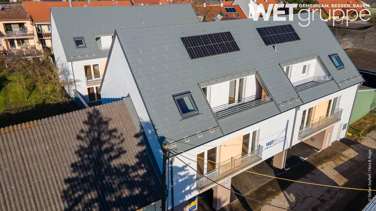 Luftaufnahme eines modernen Wohngebäudes mit Satteldach und Photovoltaikanlage.