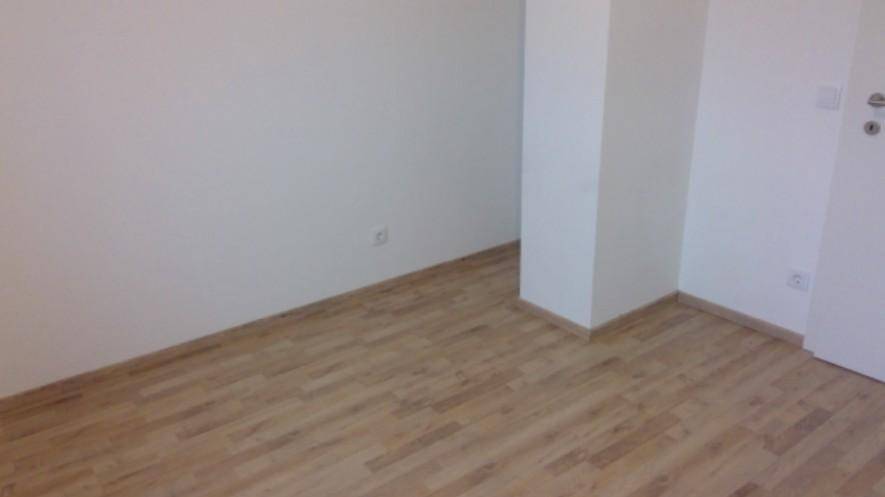 Leerer Raum mit Laminatboden und weißen Wänden, bereit zur individuellen Gestaltung.