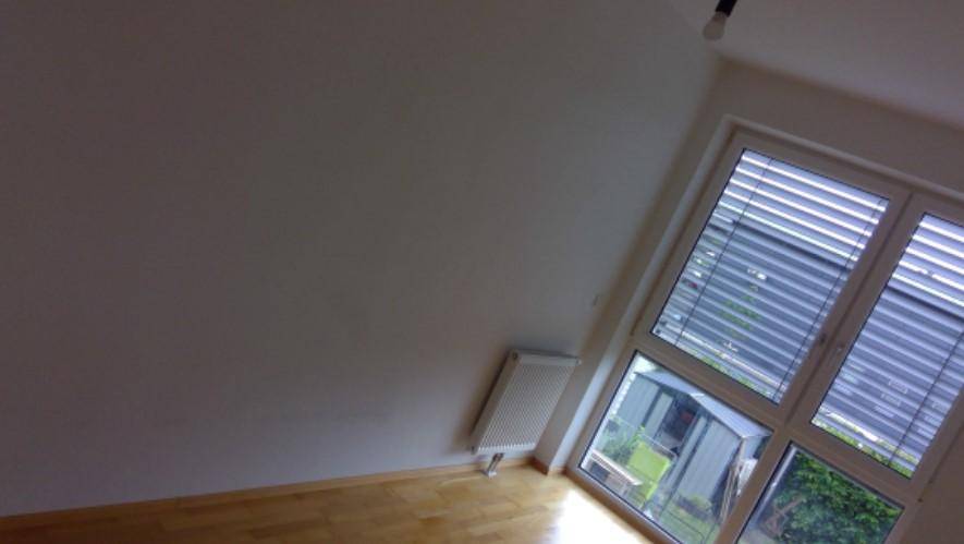 Heller, unmöblierter Raum mit Holzfußboden und großem Fenster, das viel Tageslicht hereinlässt.