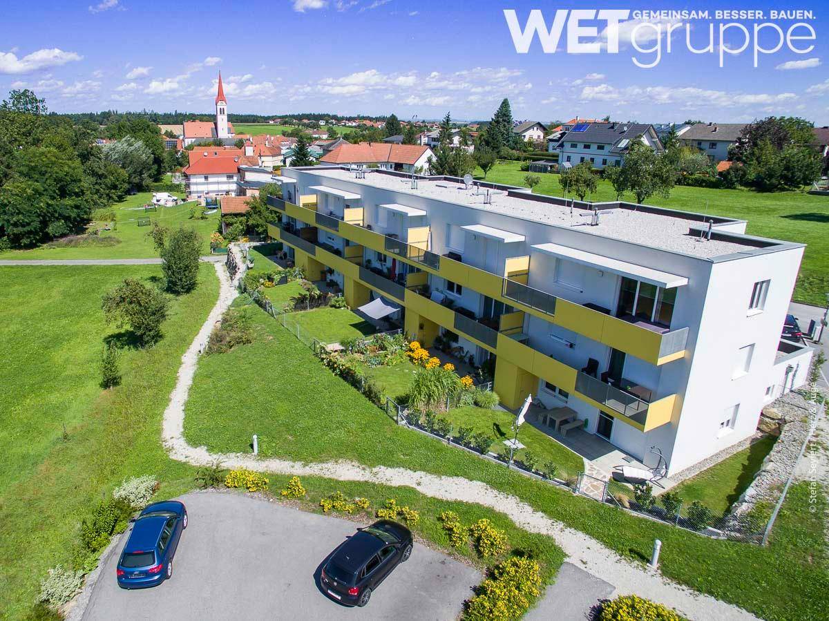 Luftaufnahme der modernen Wohnanlage mit umliegenden Grünflächen und Blick auf die Ortschaft.