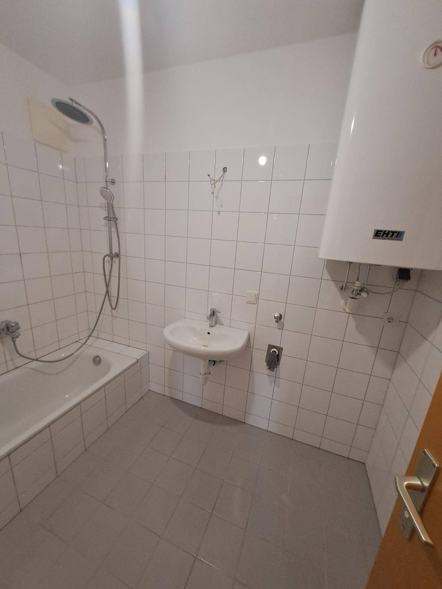 Badezimmer mit Badewanne, Dusche, Einzelwaschbecken und weiß gefliesten Wänden.