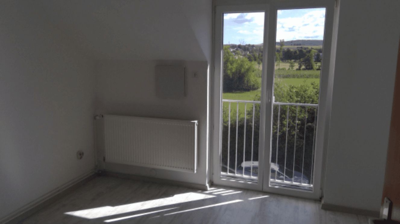 Lichtdurchflutetes Zimmer im Dachgeschoss mit französischem Balkon und weitem Blick ins Grüne.