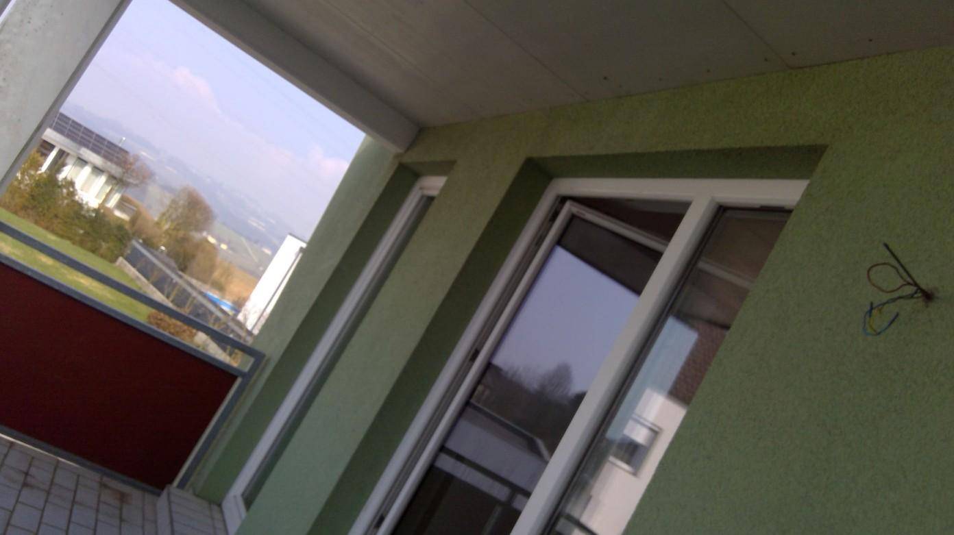 Blick vom Balkon auf die Umgebung mit weiteren Gebäuden und grüner Landschaft.